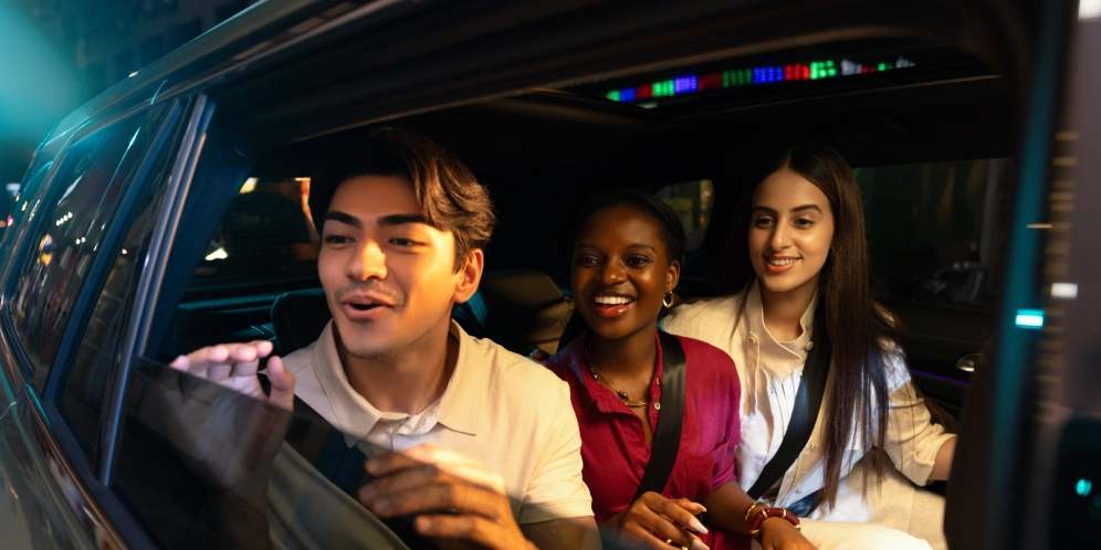 three people smiling inside a car